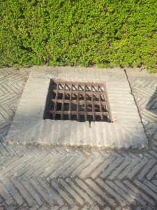 drain grate in raised brick surround along herringbone laid brick path