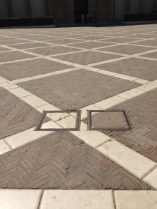 fields of rougher dark red bricks herringbone laid in concrete between smooth white stone slab dividing lines - including 2 custom-made drain covers