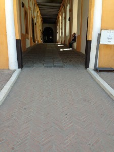 overview of inclined transition from herringbone laid dark red bricks to covered path of cobble fields between flagstones all set in concrete