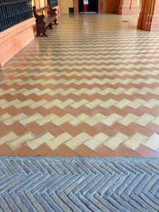 transition from yellow brick, herringbone laid in concrete, to glazed tiles, herringbone laid